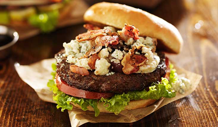A hamburger with bacon and blue cheese on top of it.
