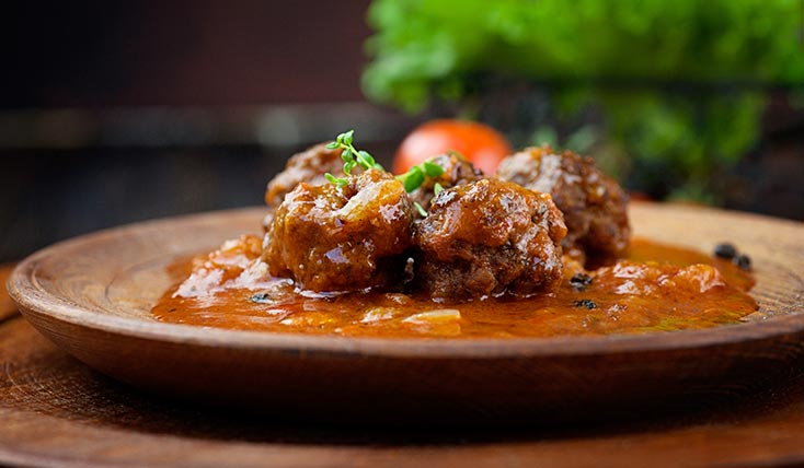 A plate of meatballs in sauce on a table.