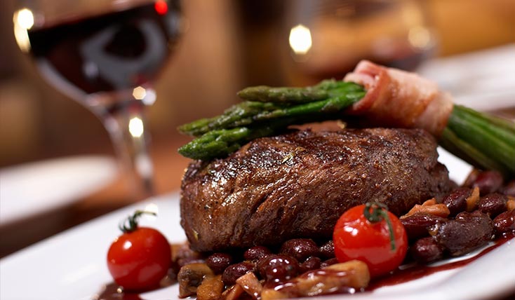 A steak with asparagus and tomatoes on the side.